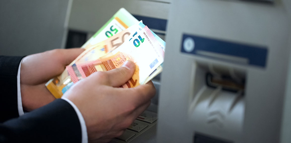 Man counting euros withdrawn from ATM, 24h service, easy banking