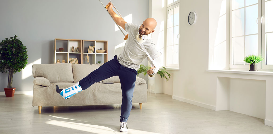 Funny positive man with numerous physical injuries having fun during rehabilitation at home.