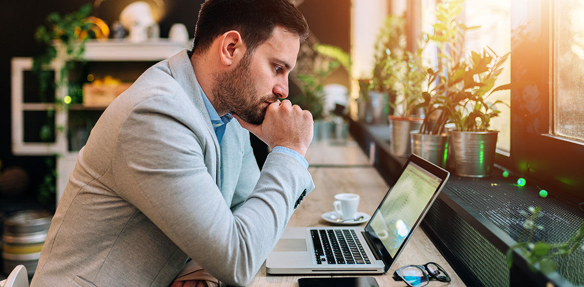 Thoughtful businessman looking at laptop screen