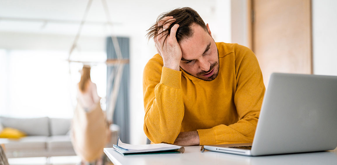 Frustrated young man working on laptop at home