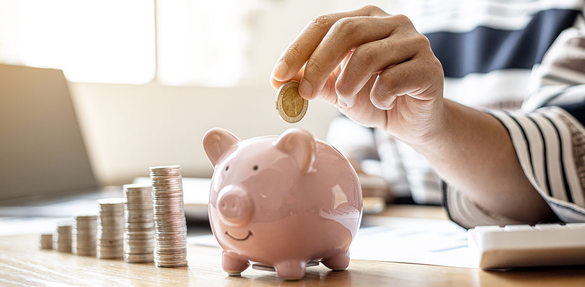 Woman putting a coin into a piggy bank in the shape of a pink pi