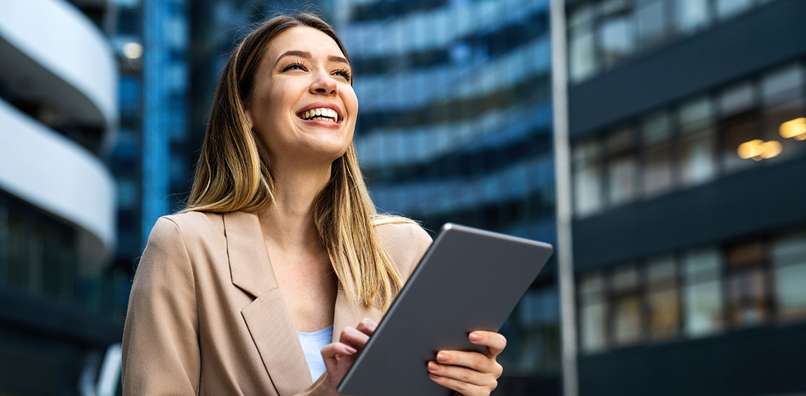 Portrait of a successful business woman using digital tablet in front of modern business building