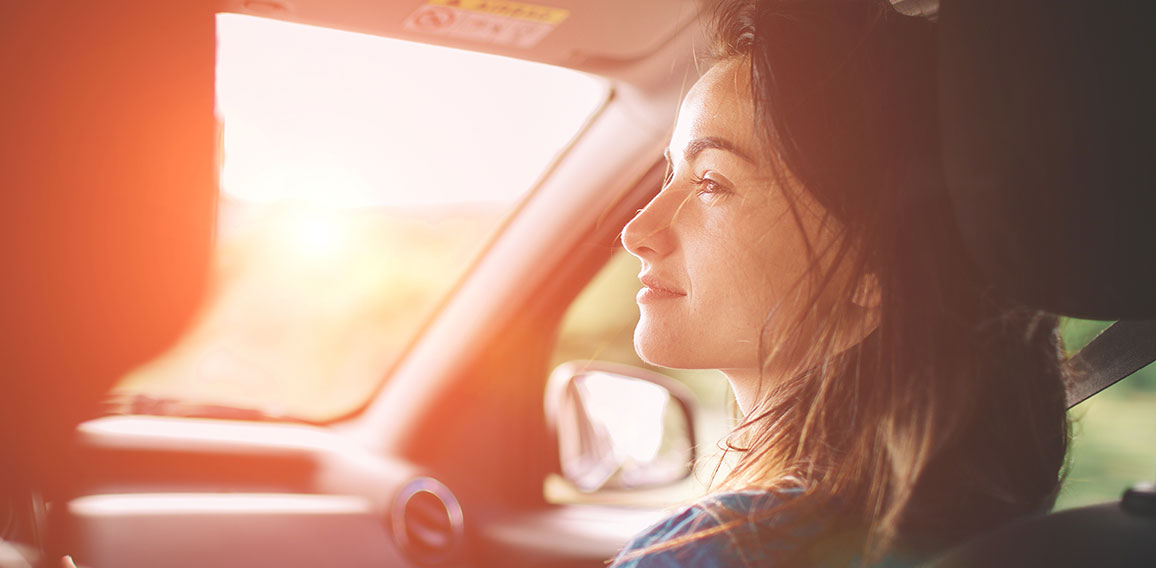 Beautiful woman smiling while sitting on the front passenger seats in the car