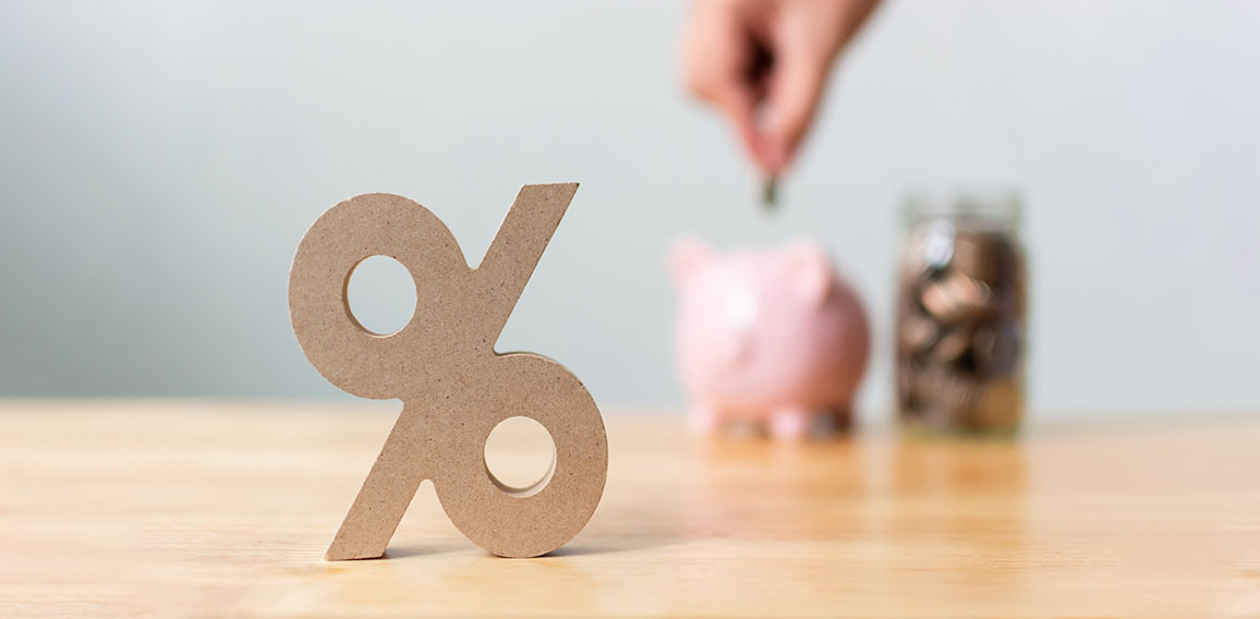 Percentage sign symbol with blurred hand putting money coin in piggy bank