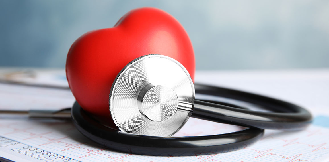 Stethoscope, red heart and cardiogram on table. Cardiology conce