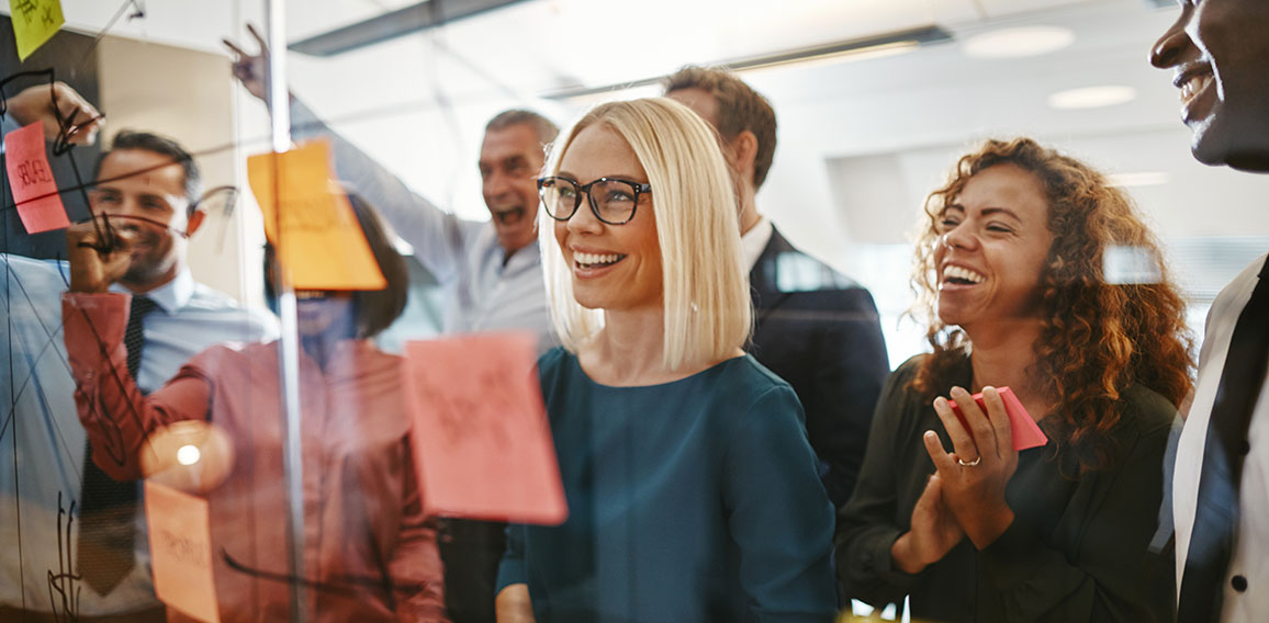 Diverse businesspeople brainstorming with notes on a glass wall