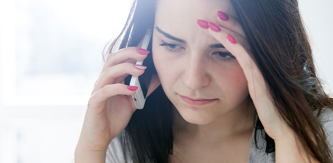 Unhappy worried woman talking on phone at home