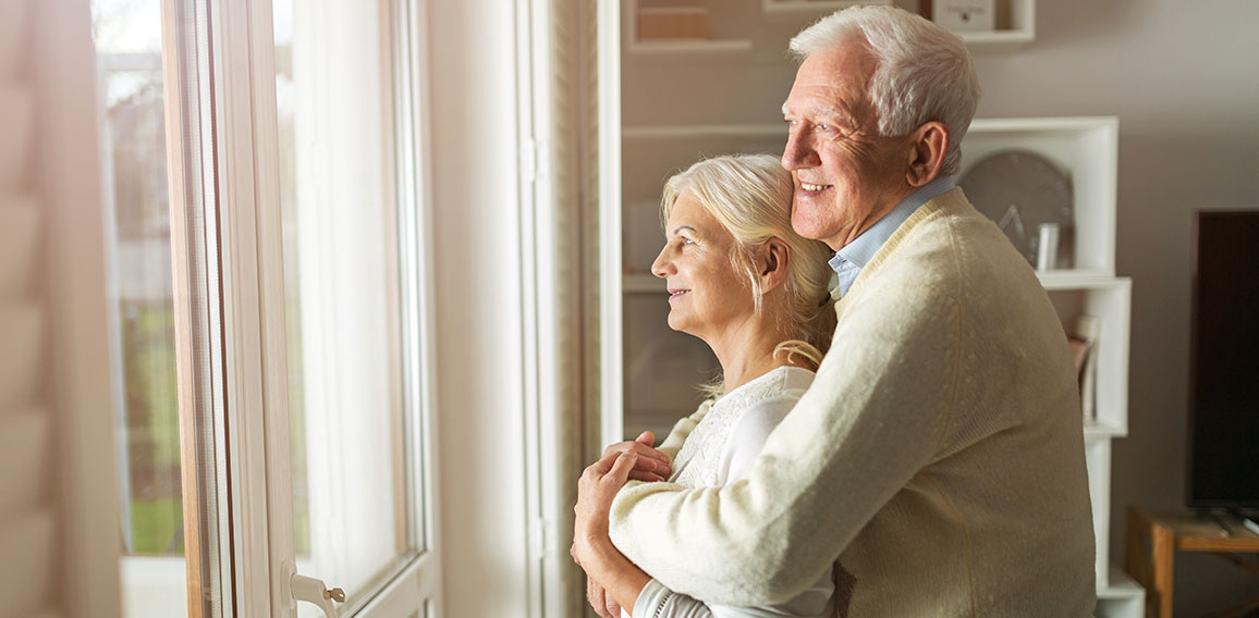 Senior couple looking out living room window