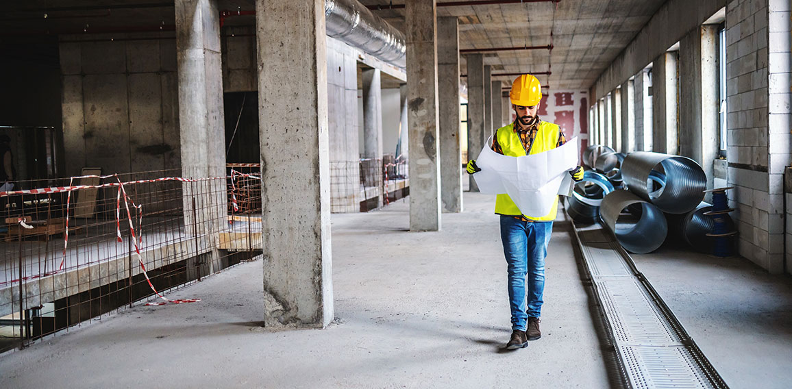 Full length of construction worker in work wear walking in build