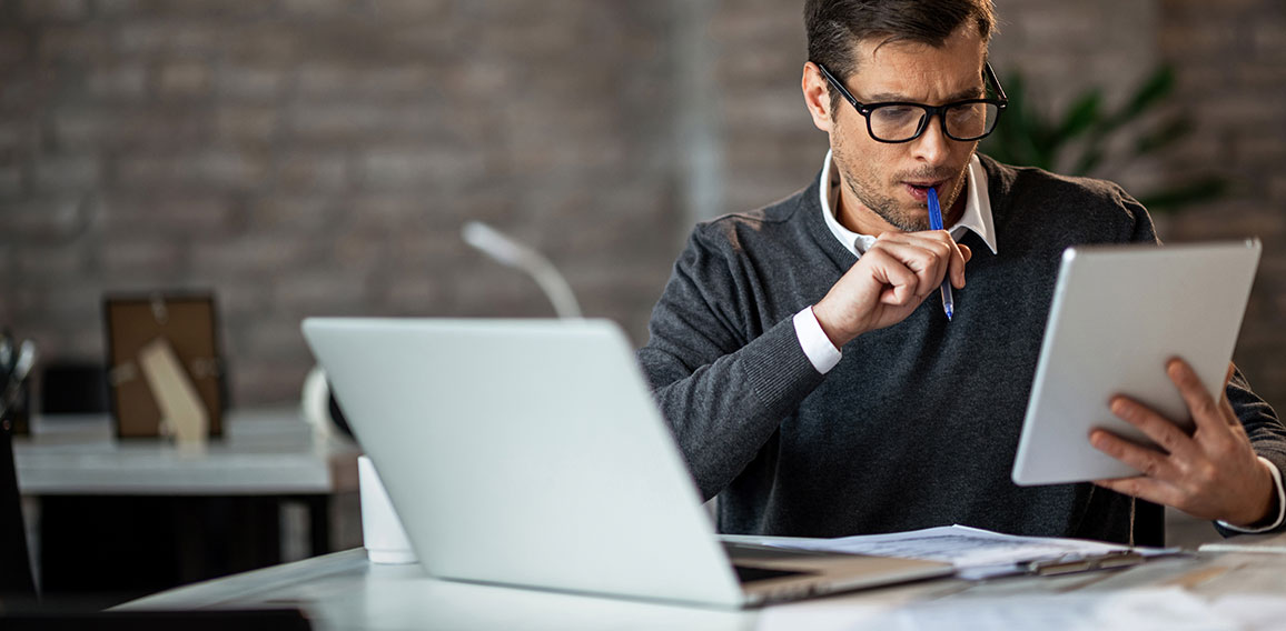 Mid adult businessman using digital tablet while working at his