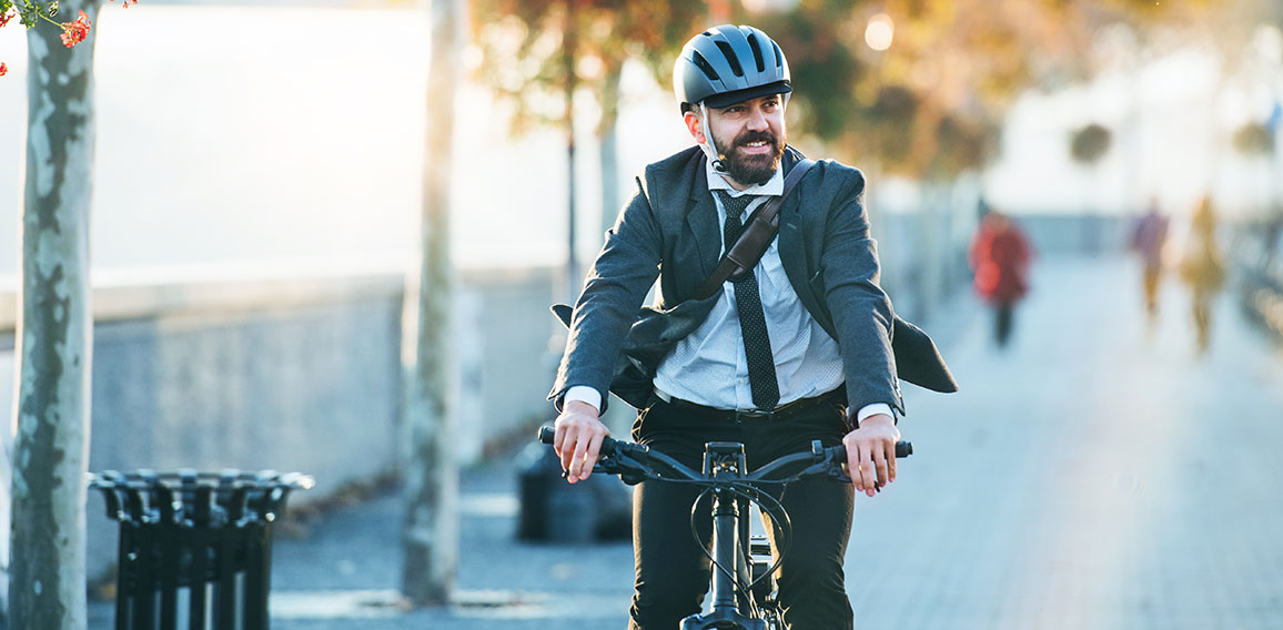 Hipster businessman commuter with electric bicycle traveling home from work in city.