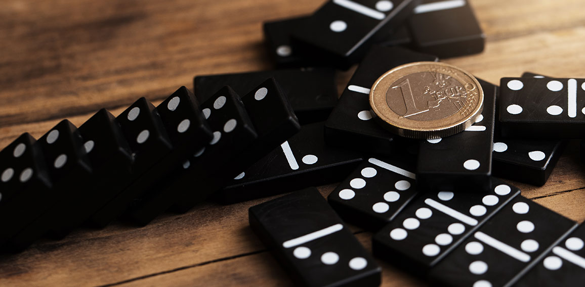 Shiny one euro coin lying on top of spilled domino tiles.