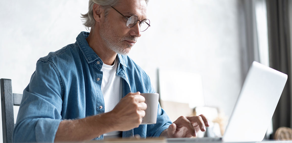 Middle-aged man working from home-office on laptop.