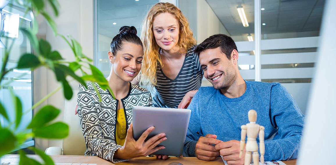 Smiling business team working together with tablet in the office