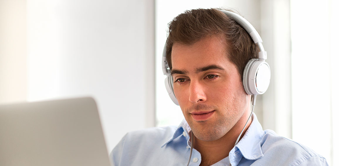 Portrait of  young handsome guy with laptop using headset