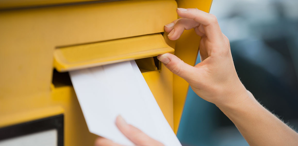 Woman's Hands Inserting Letter In Mailbox