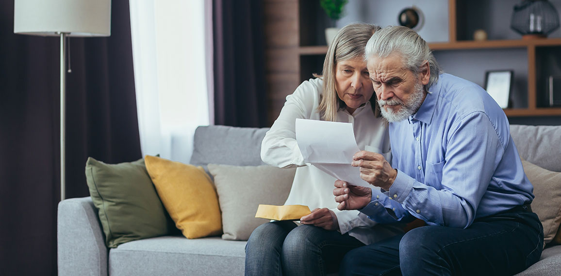 Angry frustrated document senior couple. Unhappy old family getting stressed. Serious older husband showing banking paper document bills taxes to confused elderly wife in home. Worried looking utility