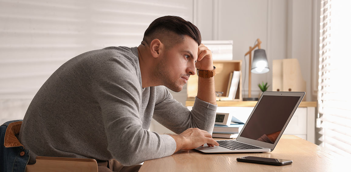 Man with poor posture using laptop at table indoors