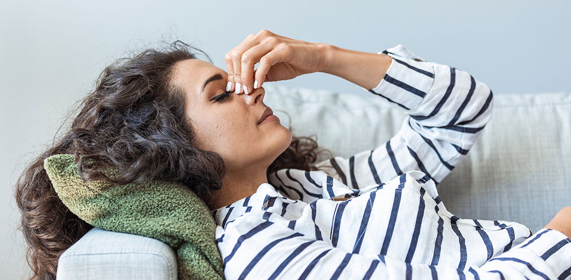 Upset depressed young woman lying on couch feeling strong headac