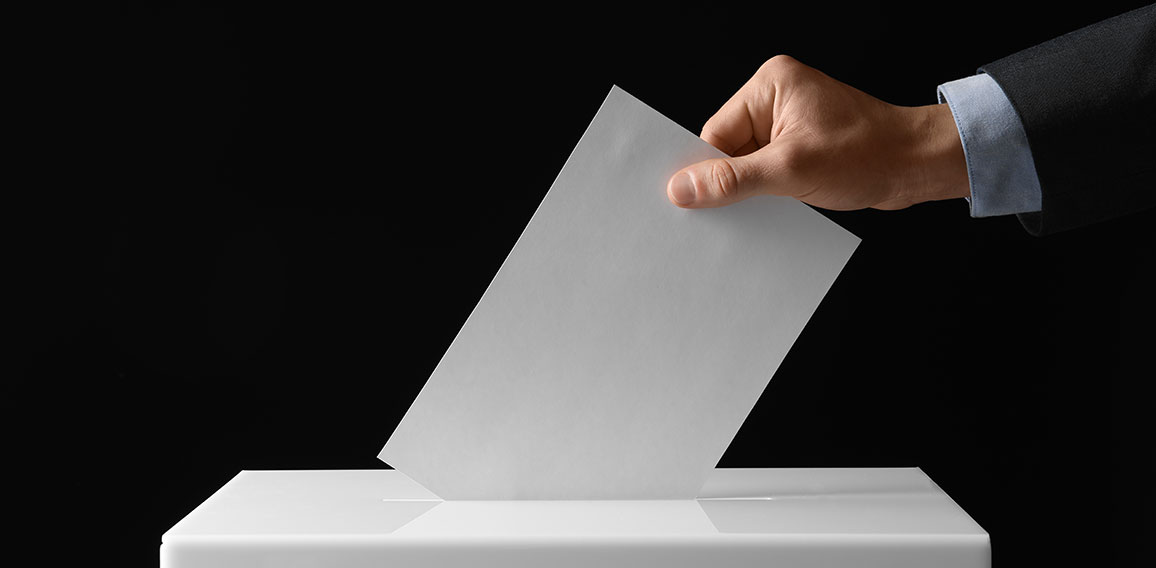 Man putting his vote into ballot box on black background, closeu