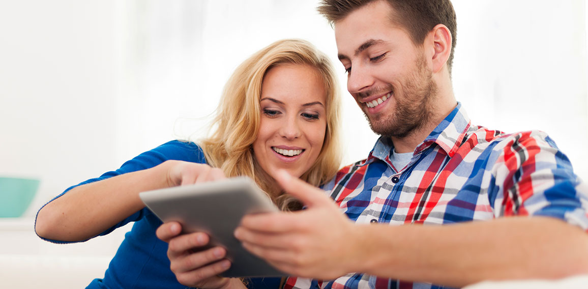 Smiling couple using digital tablet at home