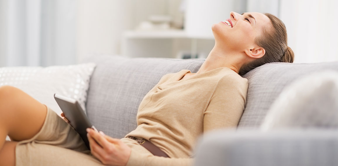 Relaxed young woman sitting on sofa with tablet pc