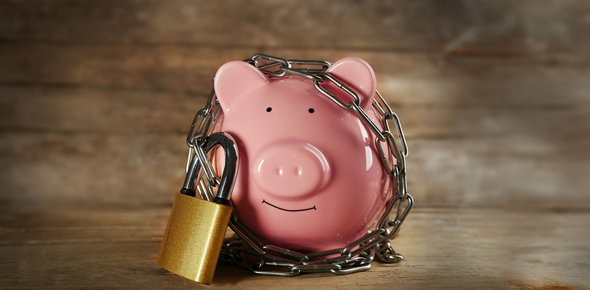 Piggy bank and chains on wooden background