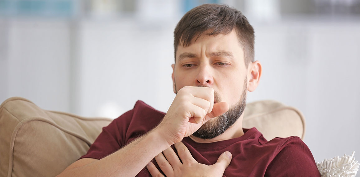 Young ill man sitting on sofa at home