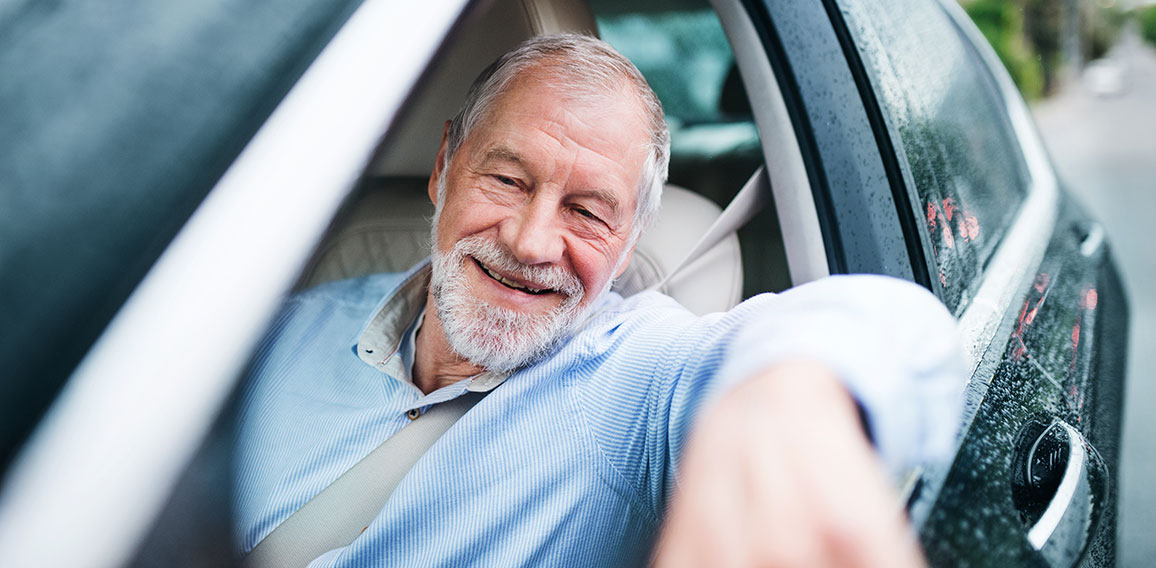 Happy senior man sitting in car in driver seat.