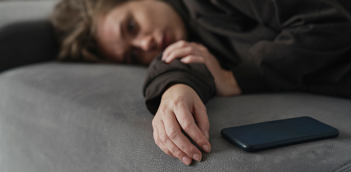 Caucasian woman with mental problem lying down with mobile phone on couch