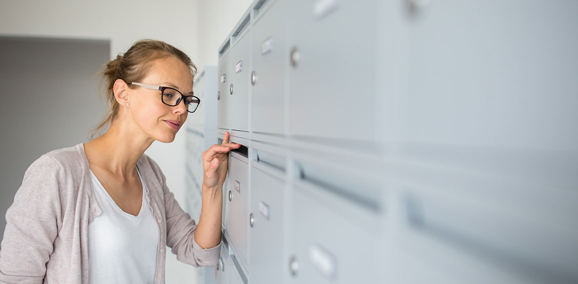 Pretty, young woman checking her mailbox for new letters