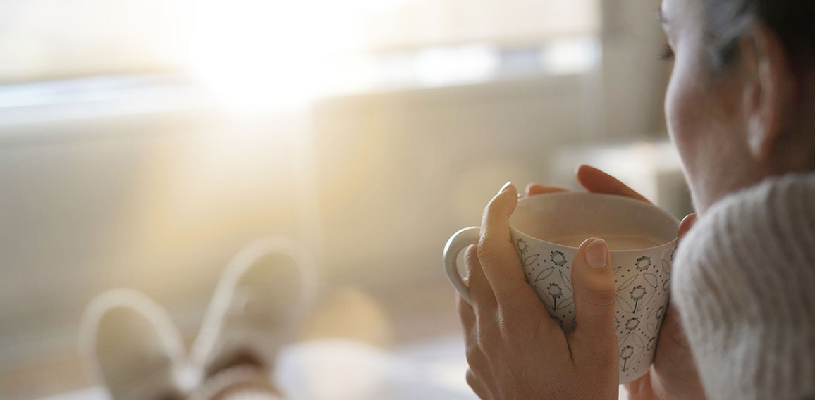 Cosy brunette at home on couch with hot drink