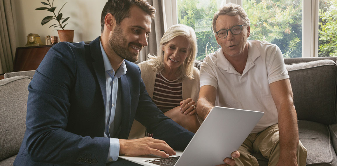 Active senior couple discussing with real estate agent over lapt