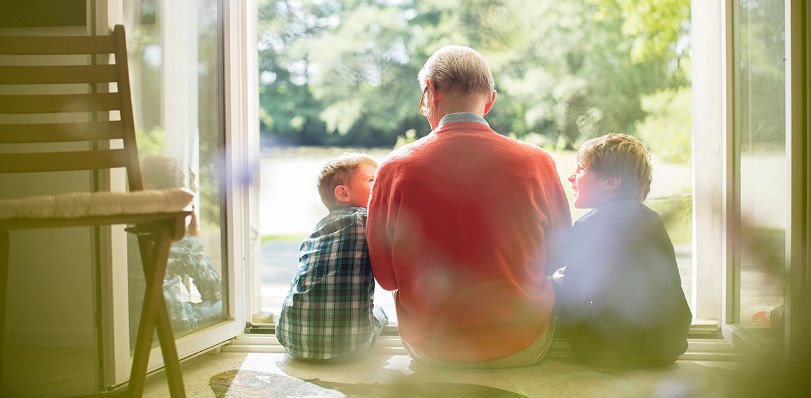 Grandfather and grandsons sitting in doorway