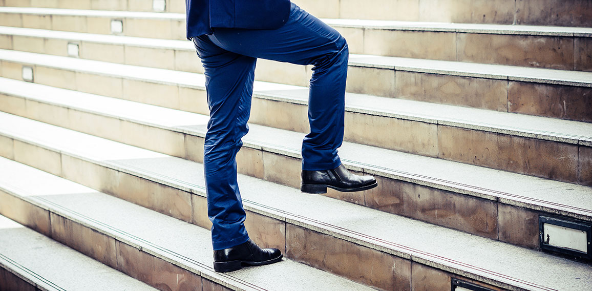 Close up of young businessman walking upstairs outside office.