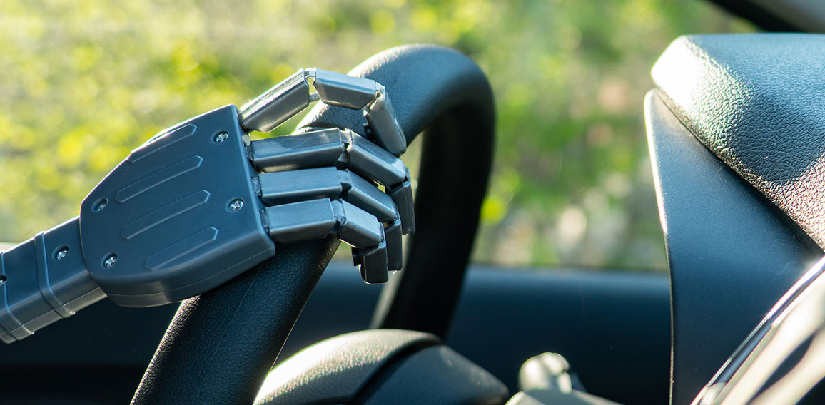 Robot arm on a steering wheel. Artificial intelligence drives a car. Autonomous vehicle concept.