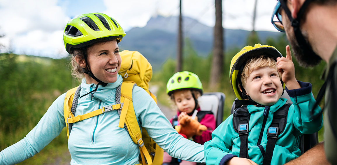 Family with small children cycling outdoors in summer nature.