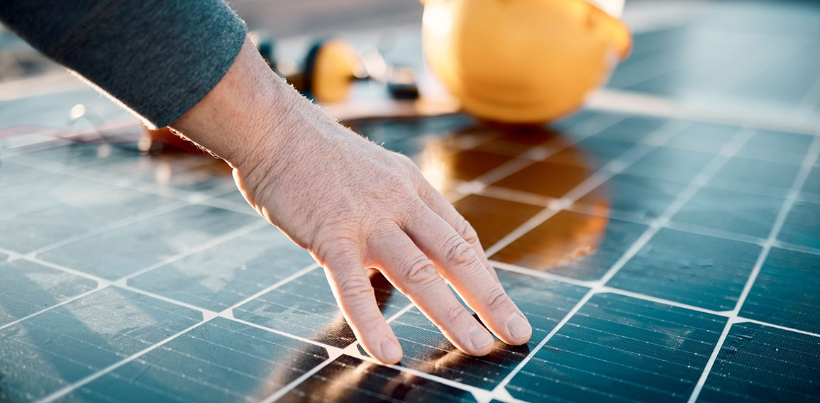 Hands, engineer and solar panel in construction for renewable energy, electricity or technology. Hand of electrician or technician feeling heated plates for quality, sun or testing power on building