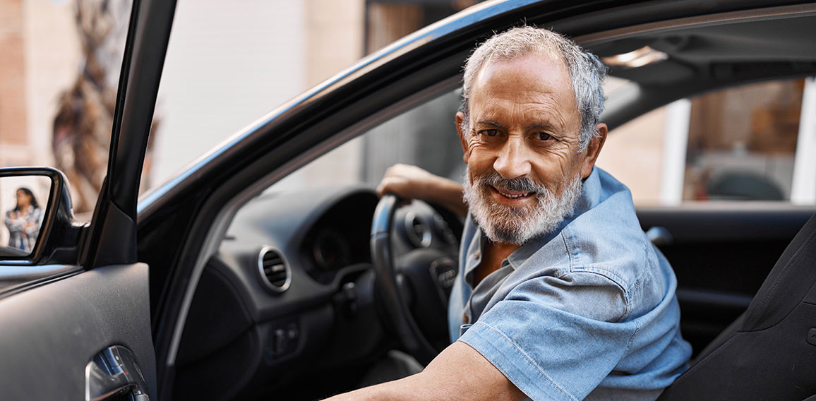 Senior grey-haired man smiling confident opening car door at street