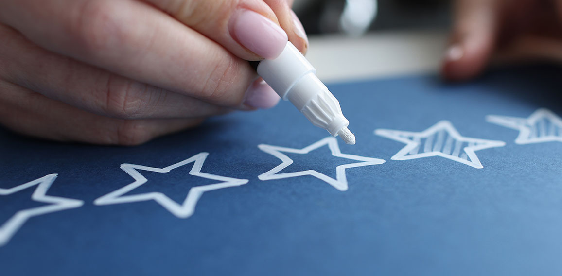 Female hand crossing out service quality rating stars with white marker closeup