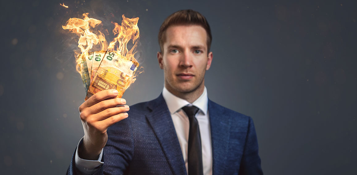 Businessman holding burning money in his hand