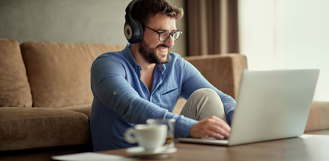 man with headphones using laptop in his home