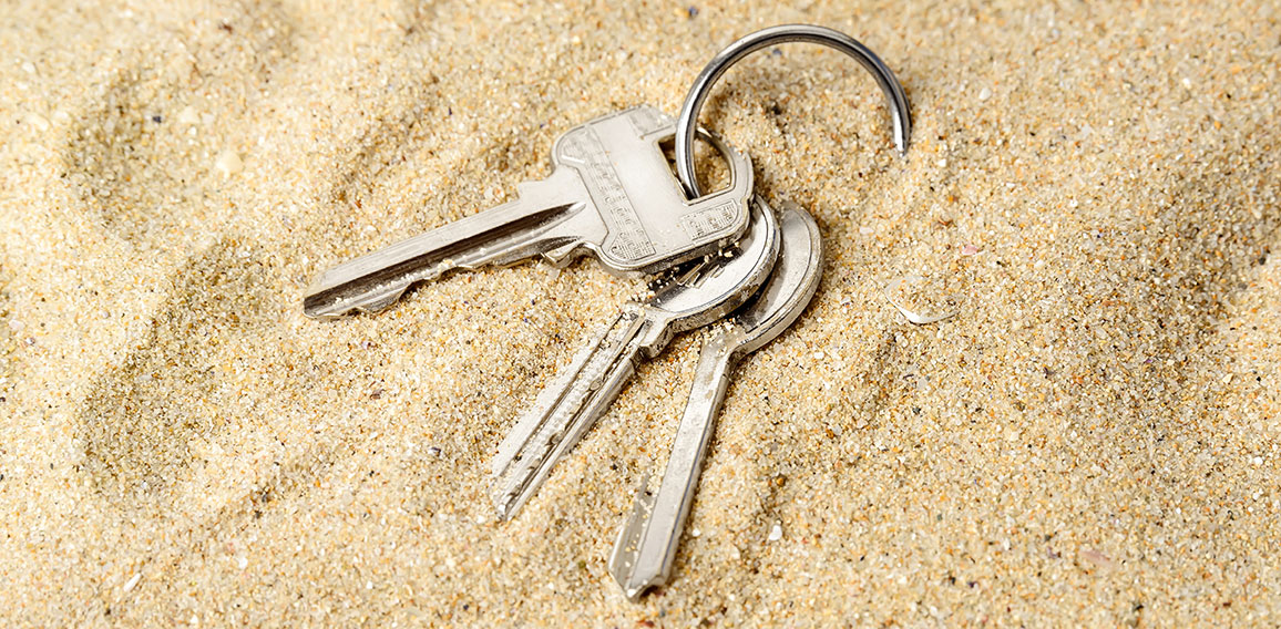 Ring with three home keys on a sea sand. Forget or fall house keys while relaxing on the beach. Accidentally drop keys. Lose bunch of apartment keys concept.