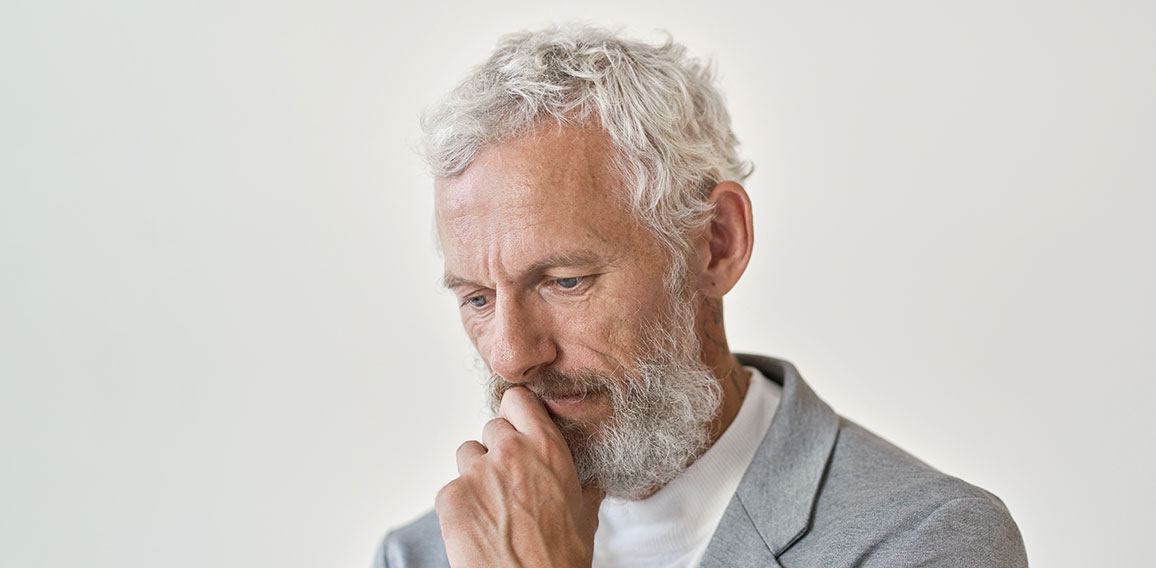 Thoughtful sad senior old business man thinking isolated on white wall.