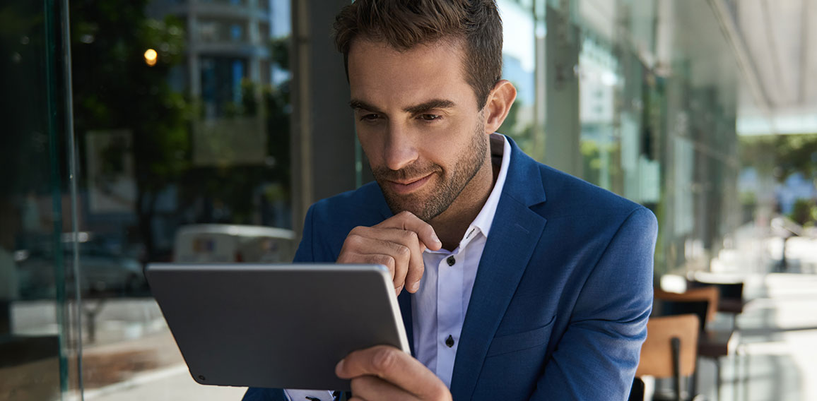 Businessman sitting outside at a cafe table using a tablet