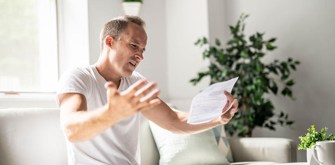 Bad news. Depressed mature man holding paper