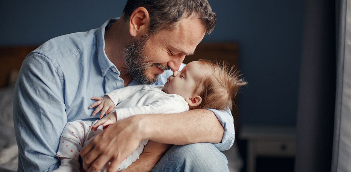 Middle age Caucasian father kissing sleeping newborn baby girl.