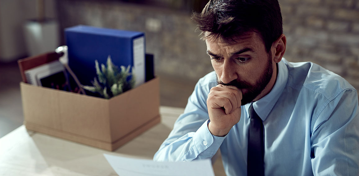 Young distraught businessman reading a notice after being fired at work,