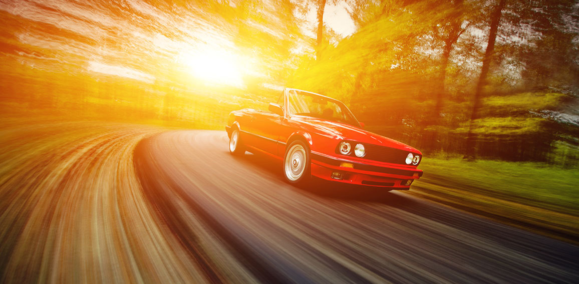 Classic red convertible sport car driving fast on the open road