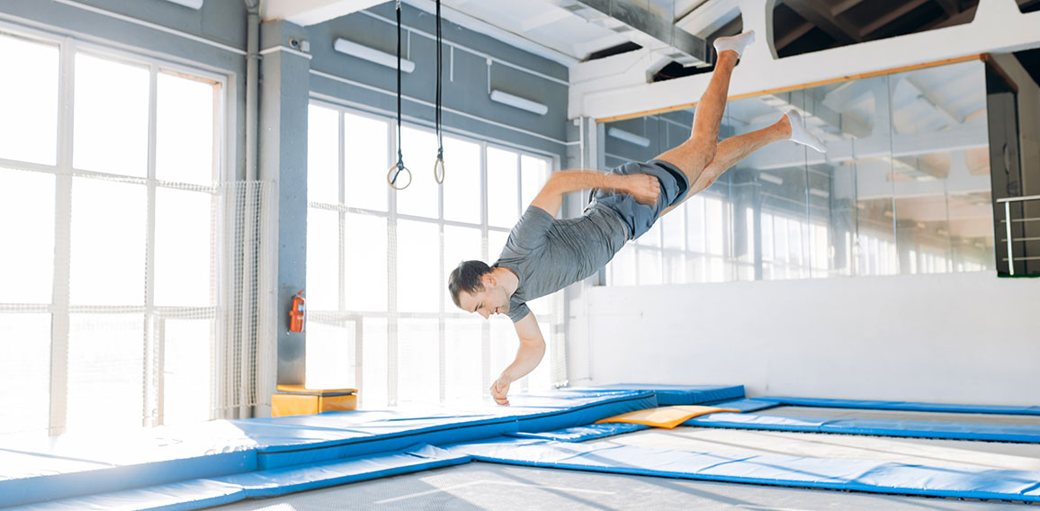 active young man is landing on mats during workout.